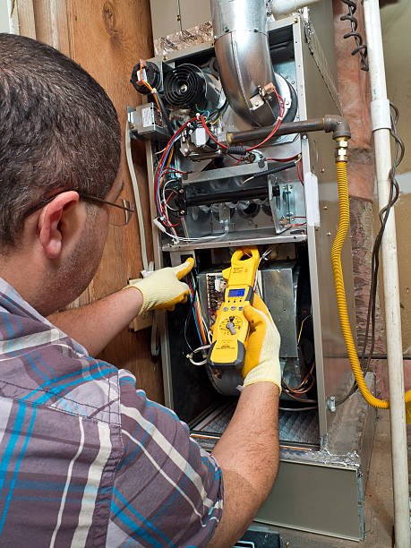 HVAC technician inspecting and testing a residential gas furnace with professional diagnostic equipment